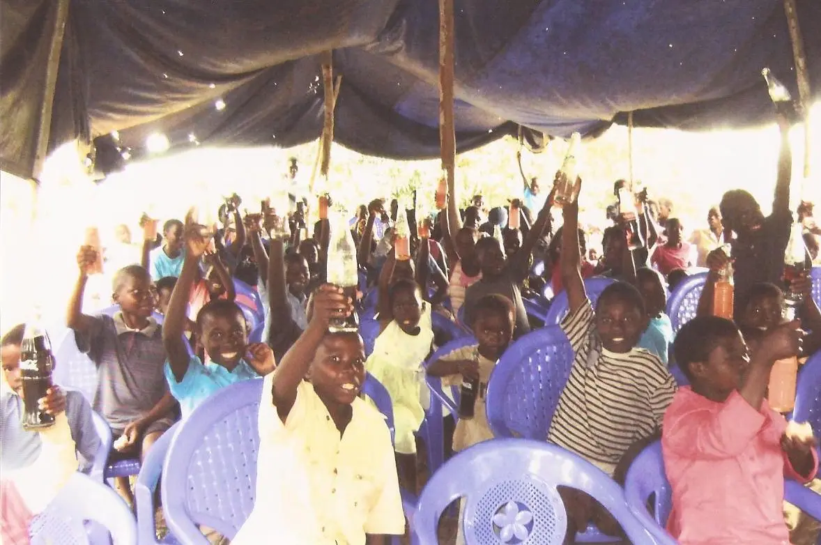 Children raising their hands together under the tent