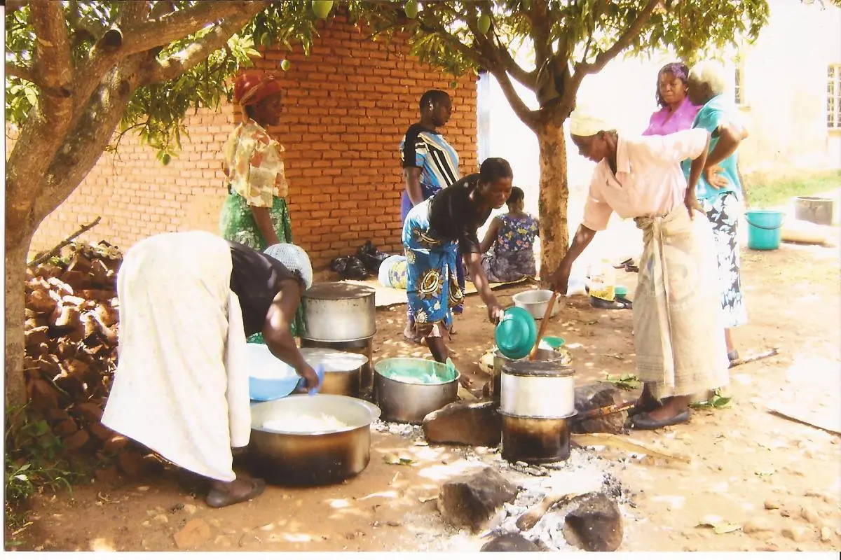 Volunteers cooking meals in large pots over an open wood fire